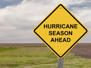 Hurricane season ahead warning sign, clouds and empty field in background