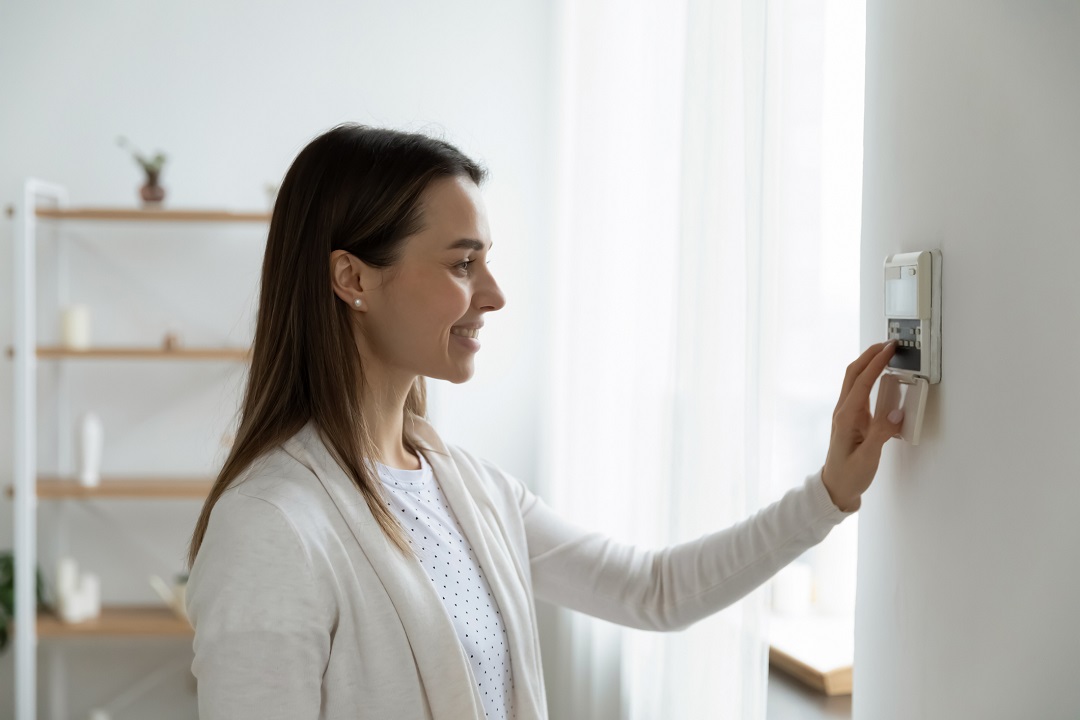 Smiling woman adjusting degrees set comfortable temperature using thermostat