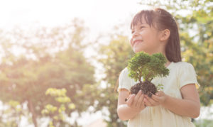Little girl outside holding a tree