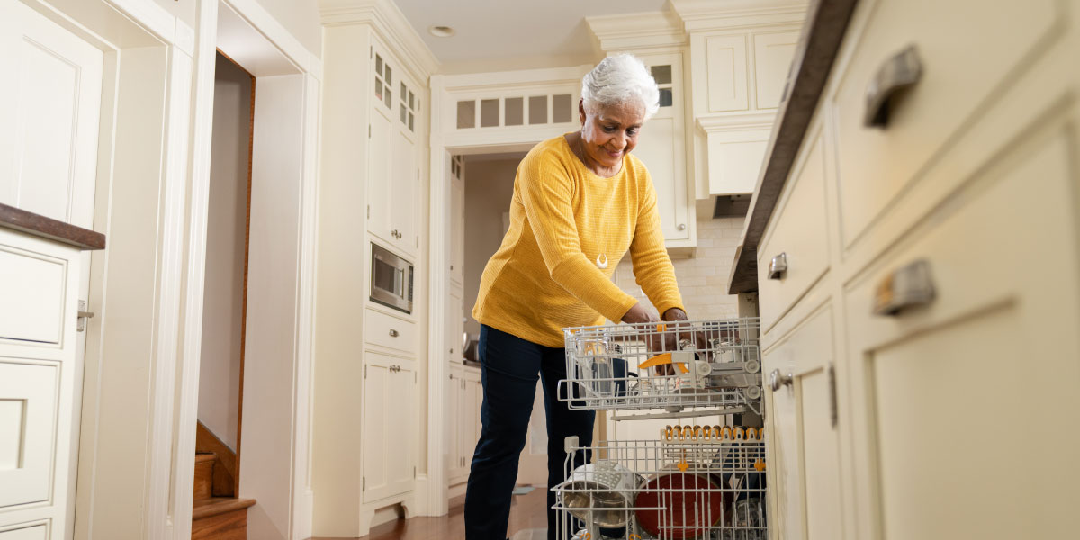 senior woman unloading a dishwasher