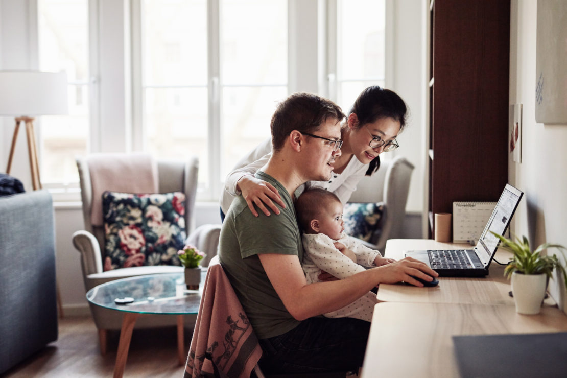 Couple looking at laptop, holding baby in lap