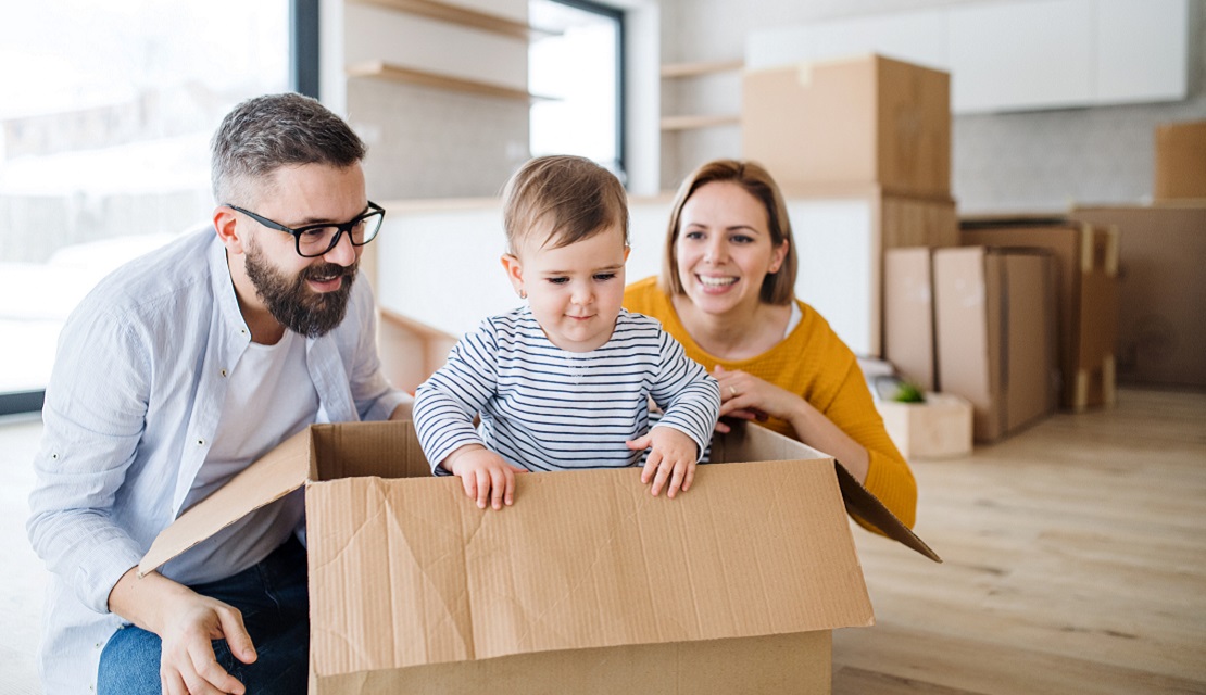 Man and woman playing with baby in cardboard moving boxes