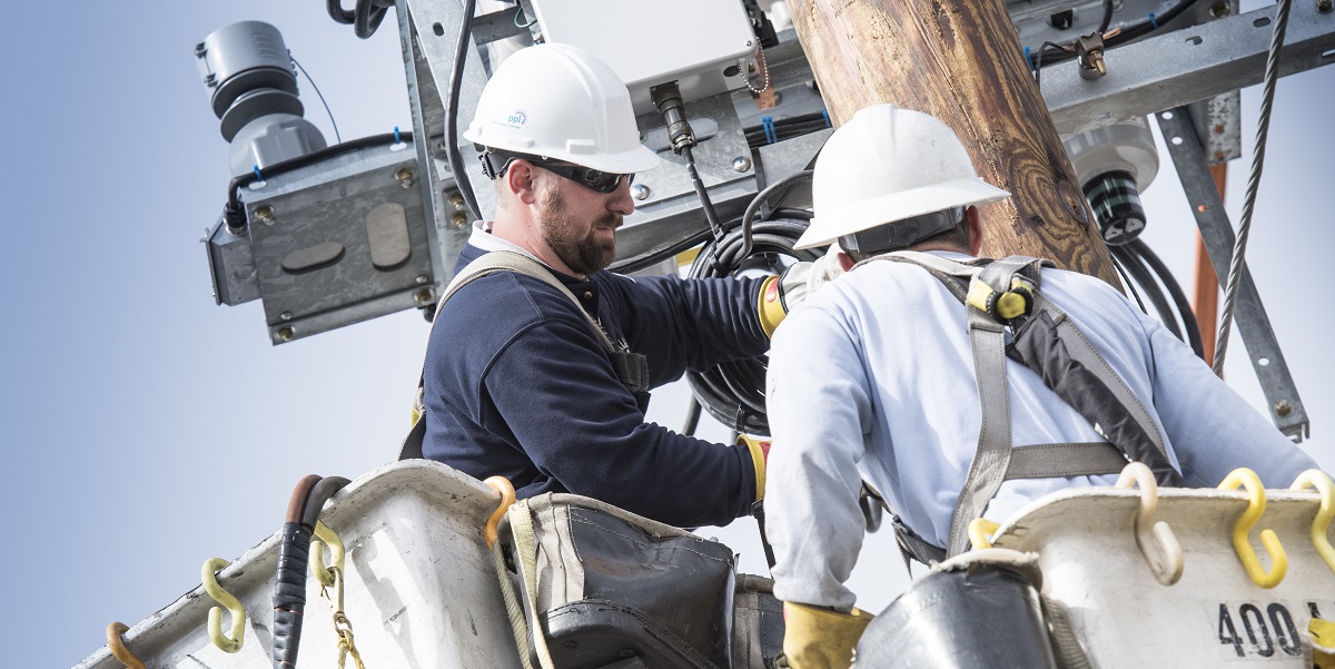 Two lineworkers install smart grid equipment
