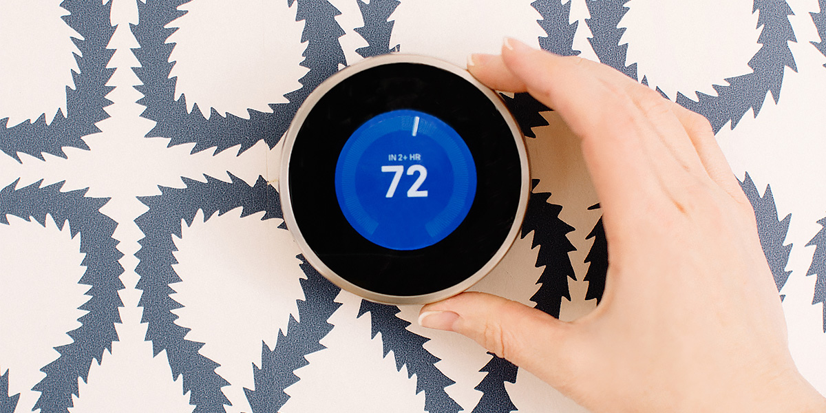Close up of hand adjusting a smart thermostat