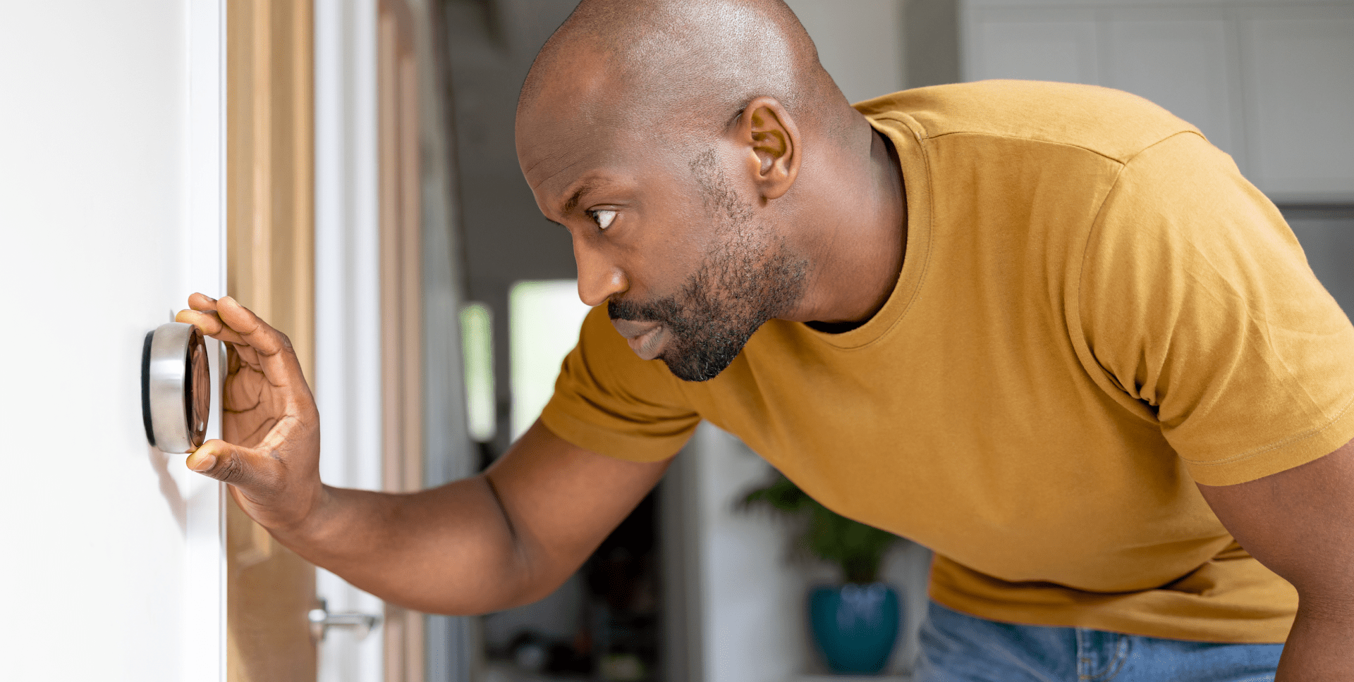 A man adjusts a wall-mounted thermostat.