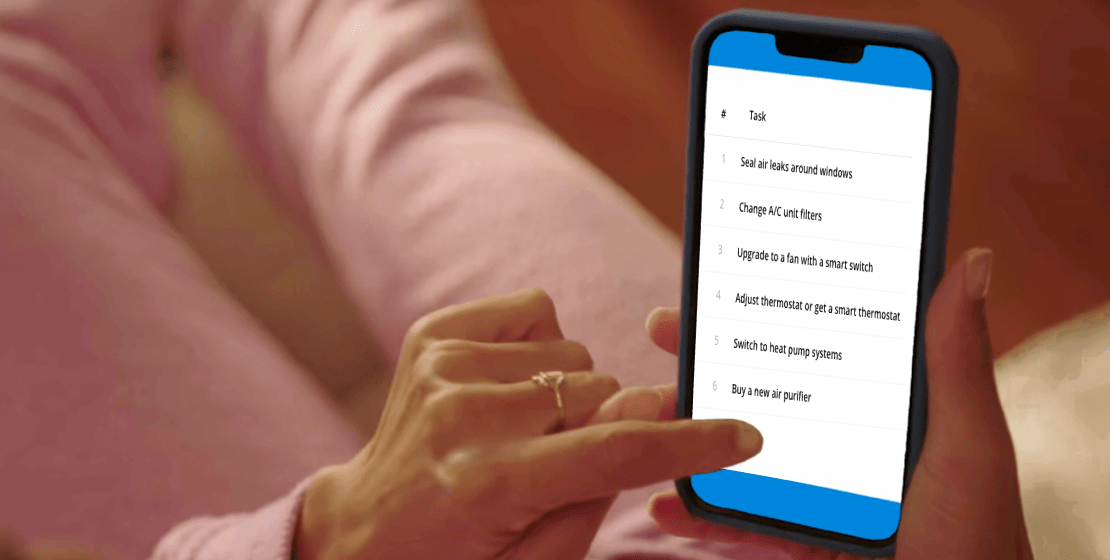 Summer cooling checklist. We’ve done the work so you can start saving fast. Image of a hand holding a mobile phone, with a list of six tasks on the screen: 1) Seal air leaks around windows. 2) Change A/C unit filters. 3) Upgrade to a fan with a smart switch. 4) Adjust thermostat or get a smart thermostat. 5) Switch to heat pump systems. 6) Buy a new air purifier.