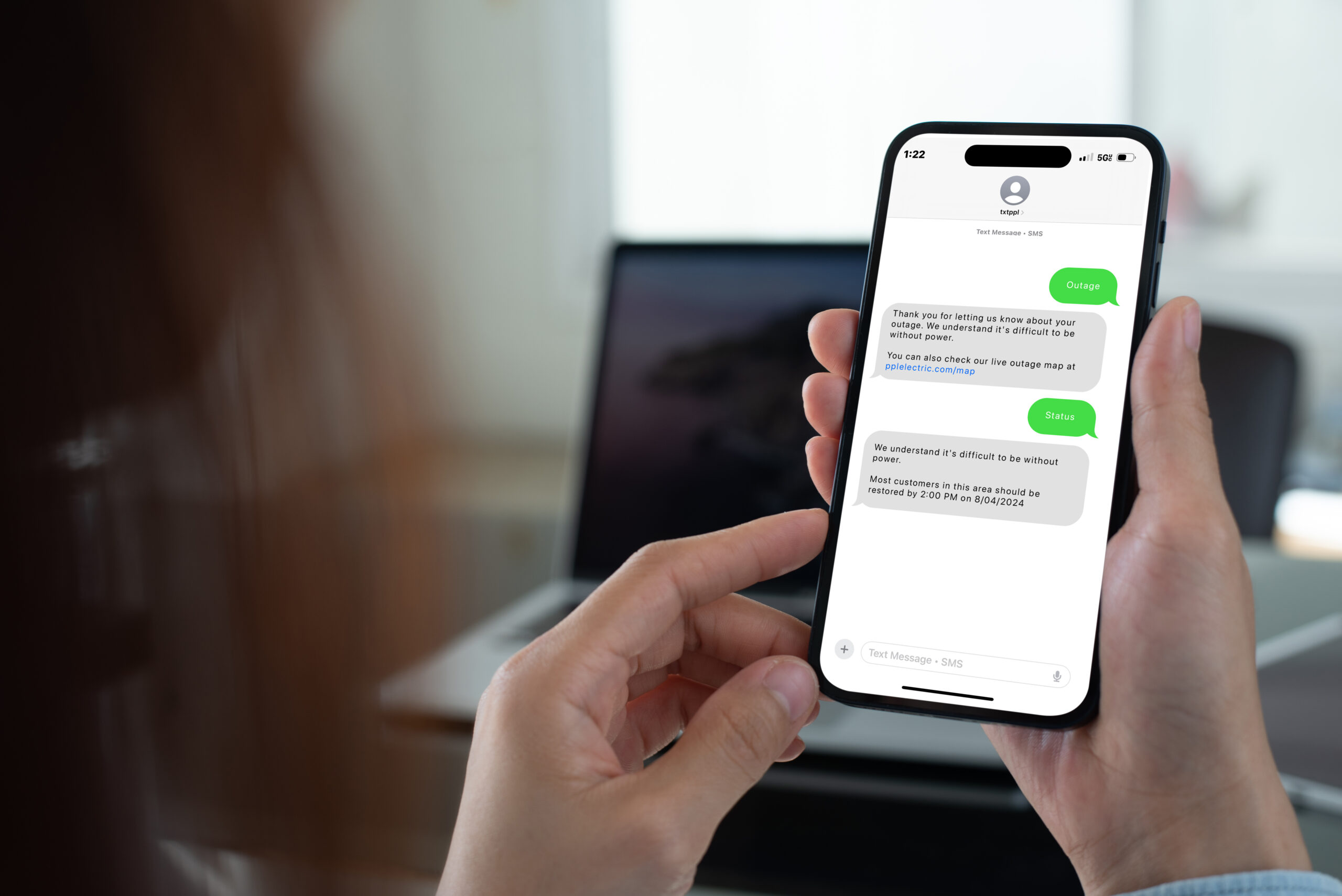 Person holding a smartphone showing a text conversation with PPL electric utility company regarding a power outage update.