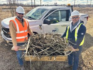 A photo of two PPL Electric Utilities employees holding up the osprey nest.