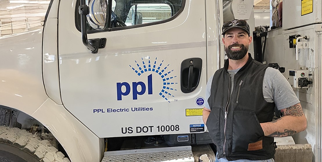 A couple walking arm in arm through a park with fall foliage on trees and leaves on the ground