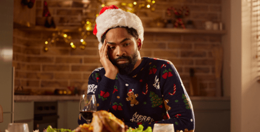 A couple walking arm in arm through a park with fall foliage on trees and leaves on the ground