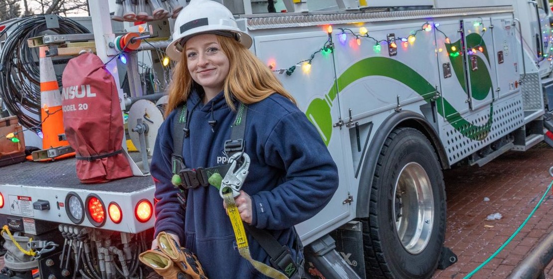A PPL Electric Utilities lineworker poses in front of a decorated PPL Electric bucket truck.