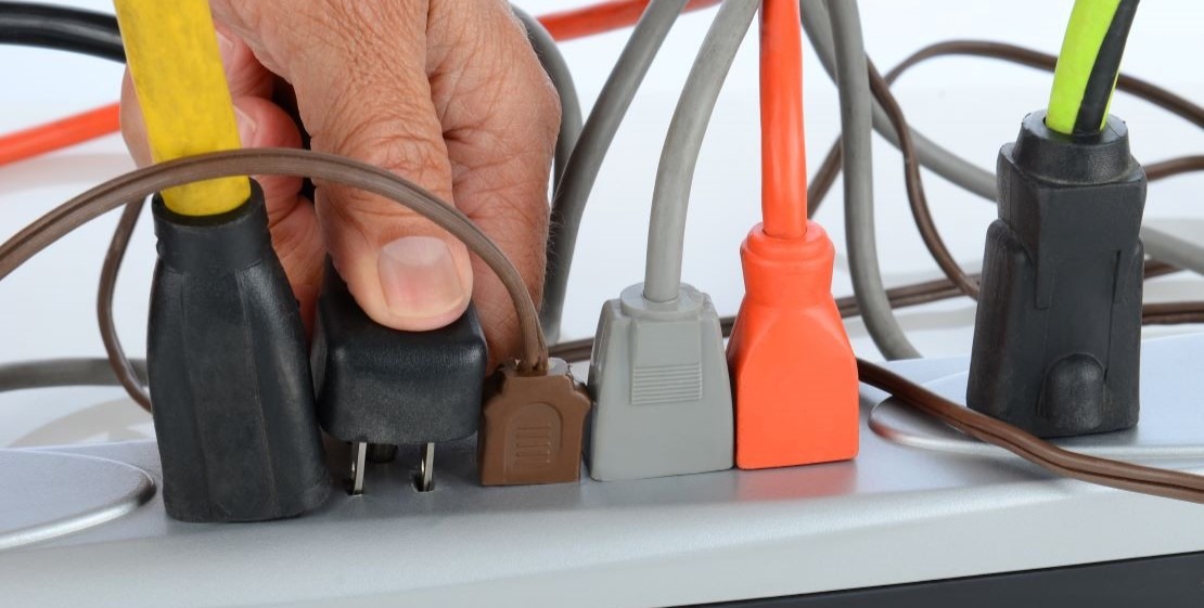 A photo of multiple plugs overloading a single multi-outlet.
