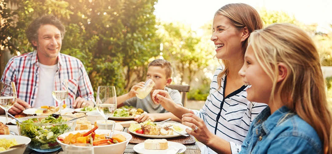 Family eating lunch together outdoors at a table
