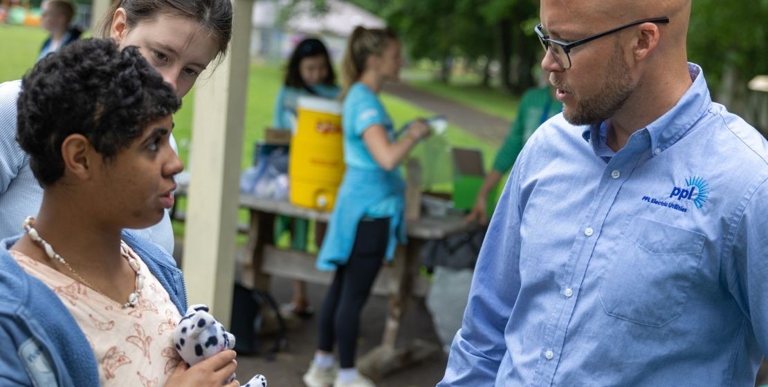 A PPL Electric Utilities employee speaking with a camper at Camp Victory.