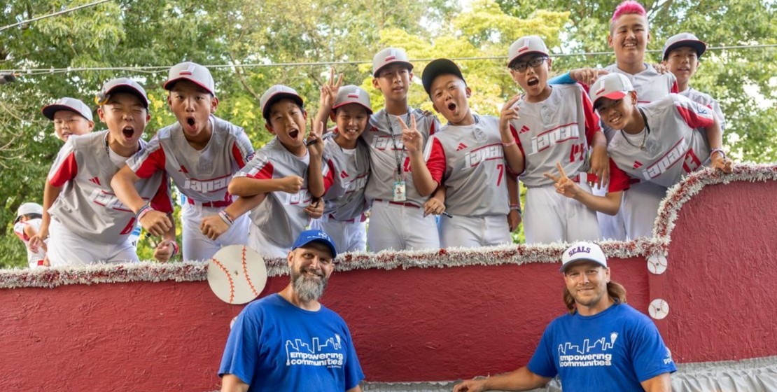 A photo of PPL Electric Utilities employees posing with Team Japan in front of their float at the annual Grand Slam Parade in Williamsport.